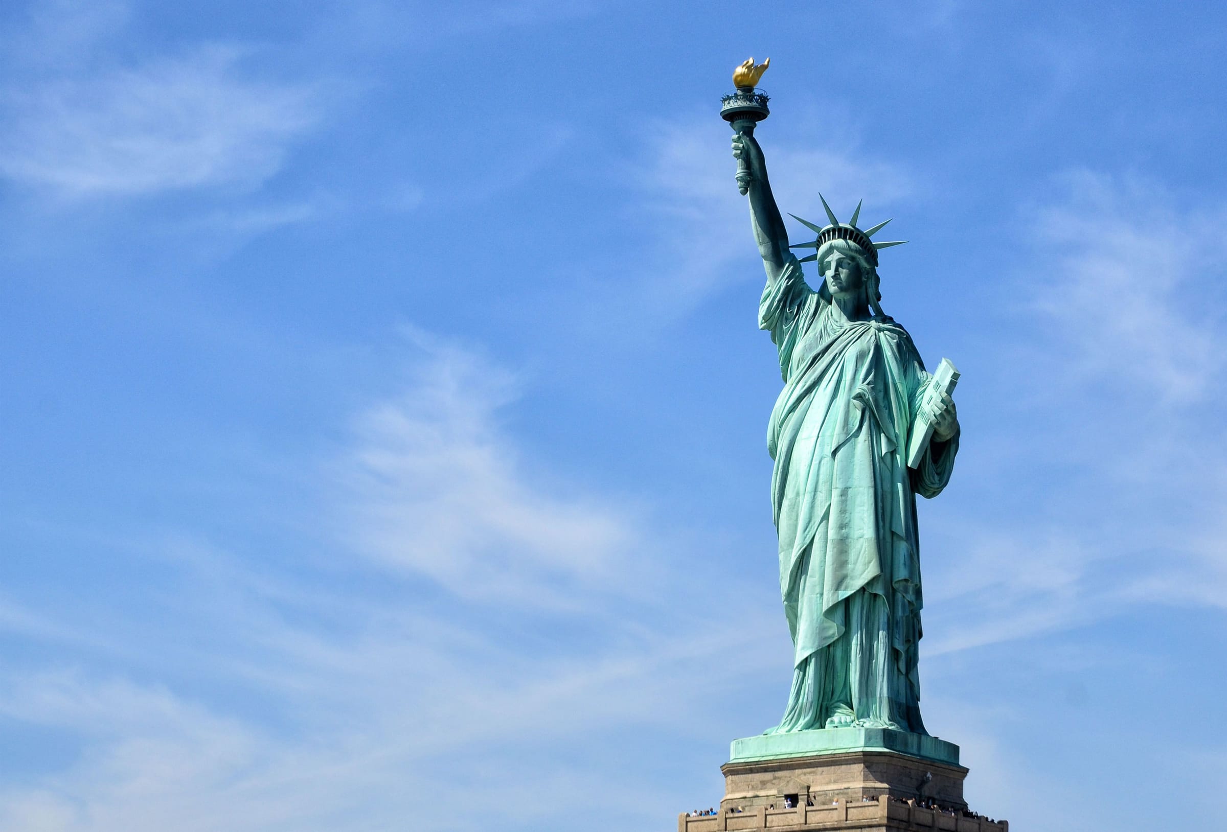 The Statue of Liberty holding her torch against a blue sky