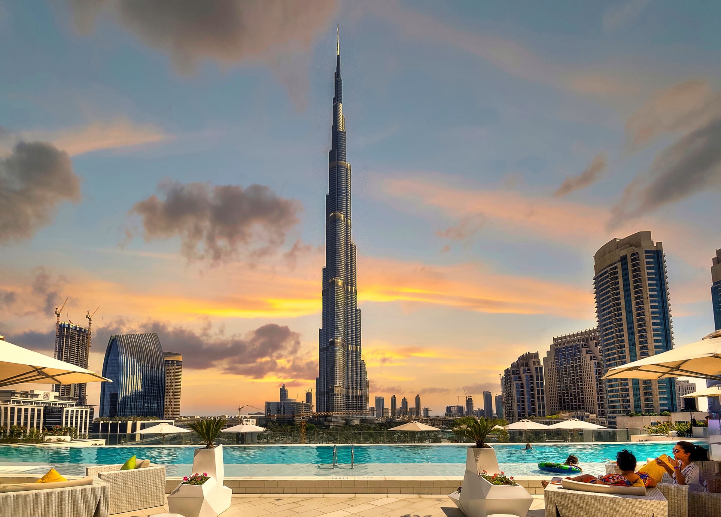 The Burj Khalifa rising over downtown Dubai at sunset, seen from a rooftop pool