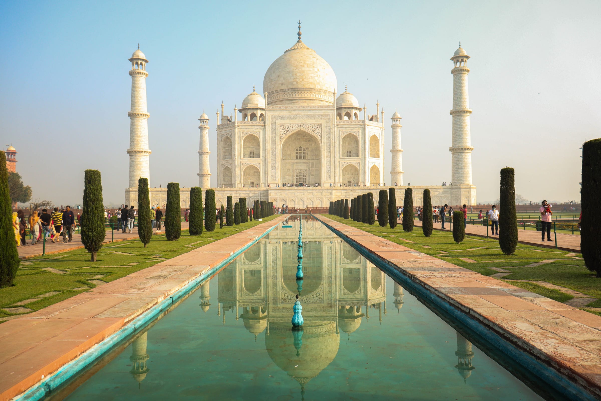 The Taj Mahal reflected in the long pool of its gardens, lined with cypress trees