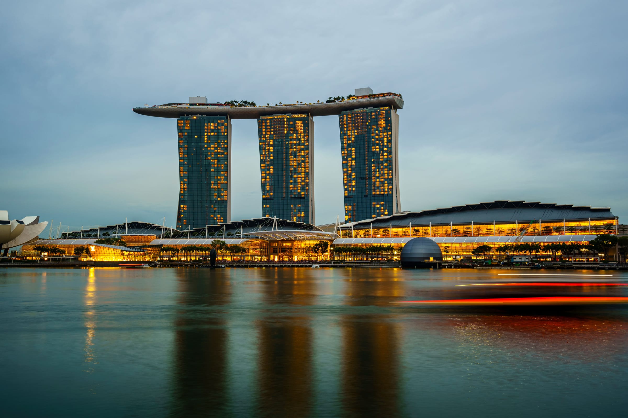 Marina Bay Sands lit up at dusk, its towers reflected in the bay