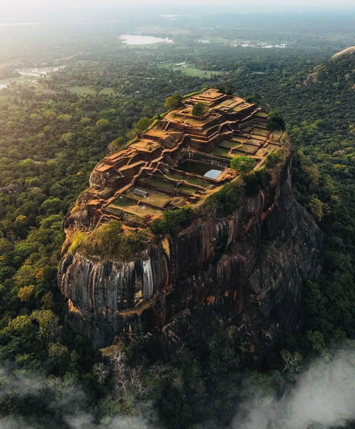 The ancient rock fortress of Sigiriya rising above the jungle in morning mist